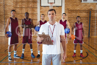 Confident coach and basketball player standing in the court