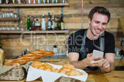 Waiter using mobile phone at counter