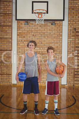 Smiling school boys holding basketball in the court