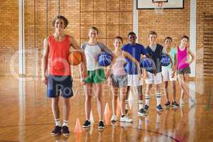 Smiling high school team holding basketball in the court