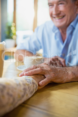 Senior couple holding hands while having coffee