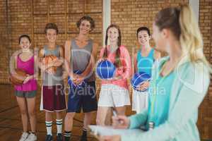 Coach talking to high school kids in basketball court