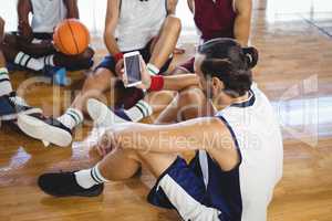 Basketball player using mobile phone while relaxing