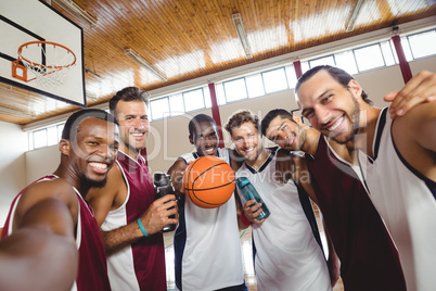 Smiling basketball players standing with arms crossed in the court