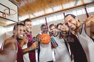 Smiling basketball players standing with arms crossed in the court