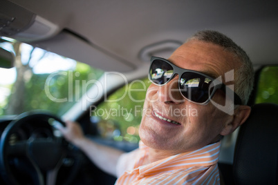 Portrait of smiling senior man wearing sunglasses in car