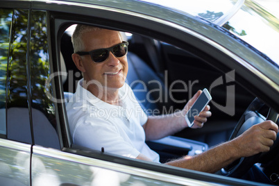 Portrait of senior man using mobile phone in car