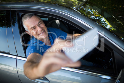 Senior man taking selfie while sitting in car