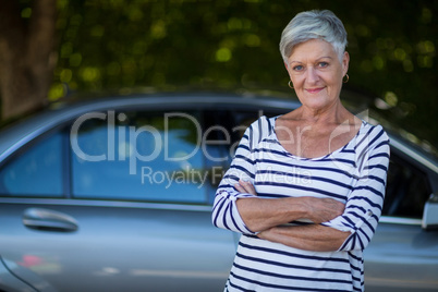 Confident senior woman standing by car