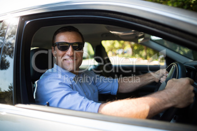 Young man wearing sunglasses while driving car