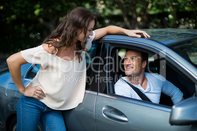 Woman looking at man sitting in car