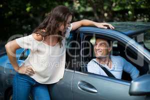 Woman looking at man sitting in car