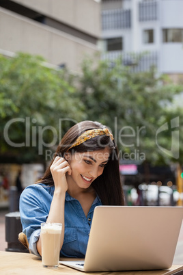 Beautiful woman using laptop while sitting at sidewalk cafe