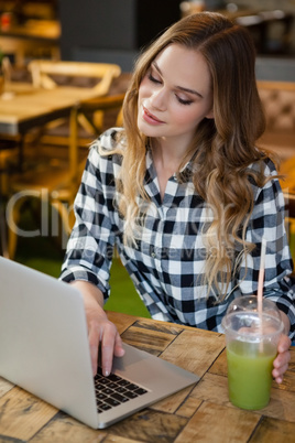 Woman using laptop at table in cafe shop