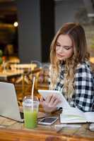 Woman looking at tablet while sitting at cafe shop