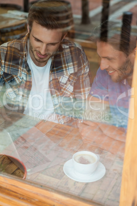 Friends using laptop while sitting by window at cafe shop