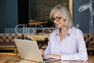 Senior woman using laptop computer while sitting at table