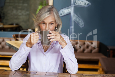 Portrait of senior woman drinking coffee while sitting at table