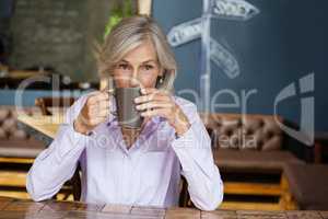 Portrait of senior woman drinking coffee while sitting at table