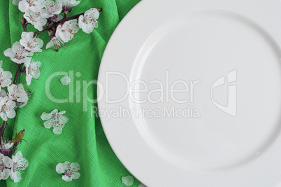Empty white dish on a green napkin with cherry blossoms
