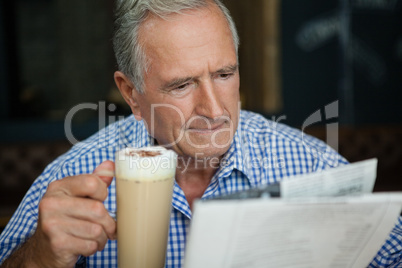 Senior man reading newspaper while sitting at cafe