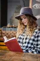 Young woman wearing hat reading book