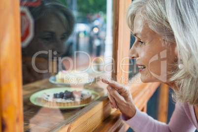 Senior woman looking at food through glass window