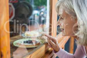 Senior woman looking at food through glass window