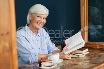 Portrait of smiling senior woman holding book