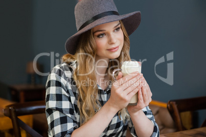 Woman looking away while holding cold coffee in cafe shop