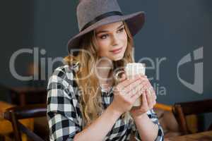 Woman looking away while holding cold coffee in cafe shop