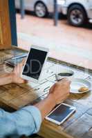 Person holding tablet computer by coffee cup at table