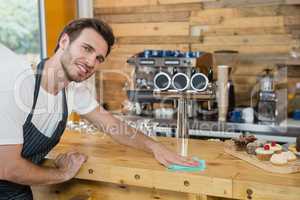 Portrait of waiter cleaning counter worktop