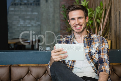 Portrait of young man using digital tablet while relaxing on sofa