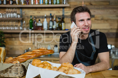 Waiter talking on mobile phone at counter