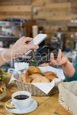 Customer paying bill through smartphone using NFC technology at counter