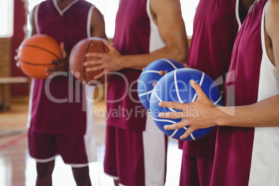 Basketball players holding basketball in court