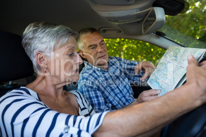 Senior couple reading map in car