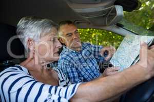 Senior couple reading map in car