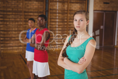 High school kids standing with arms crossed in the basketball court