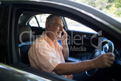 Senior man talking on phone in car