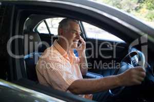 Senior man talking on phone in car
