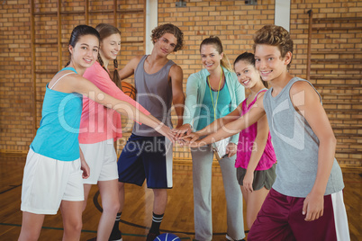 Female coach and high school kids with their hands stacked