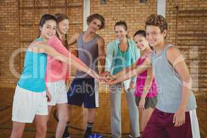 Female coach and high school kids with their hands stacked