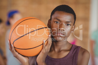 High school boy standing with basketball in the court