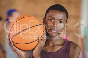 High school boy standing with basketball in the court