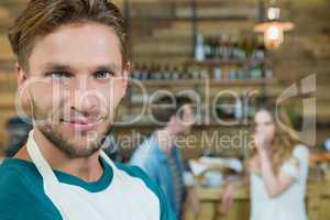 Portrait of smiling waiter and customers in background