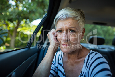 Tensed senior woman siting in car