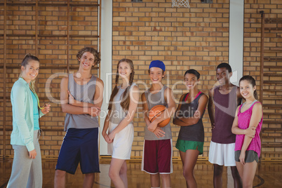 Female coach and high school kids standing in basketball court