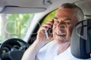 Smiling senior man talking on phone in car